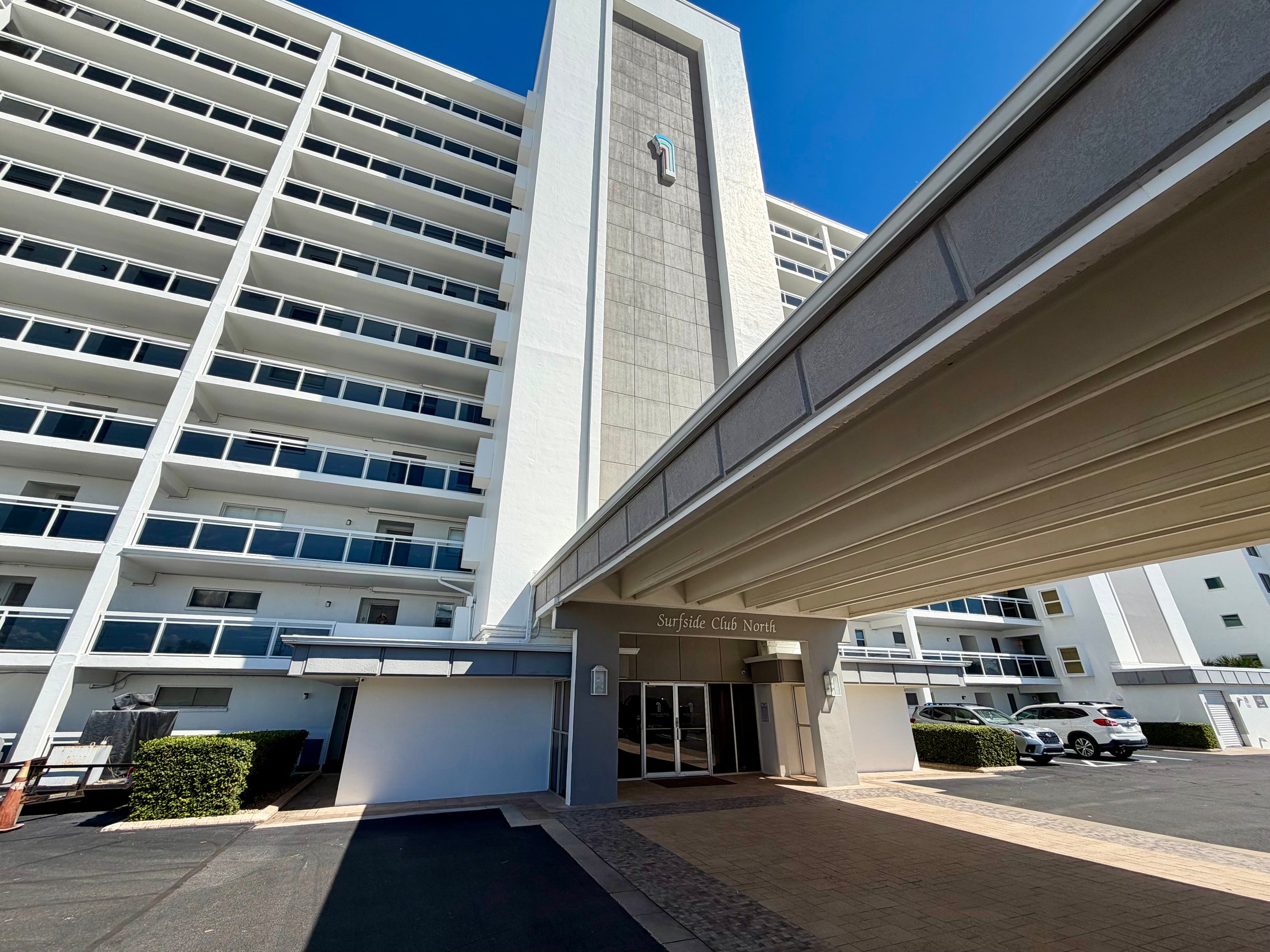 Surfside Club North condominium tower and entrance under a clear blue sky